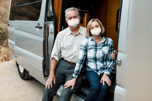 casal mais velho abraçados sentados em entrada de van.