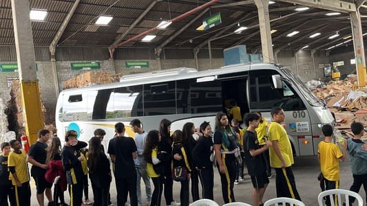 Jovens em fila ao lado de micro ônibus