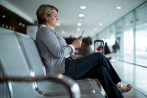 Mulher em cadeira de aeroporto mexendo em celular