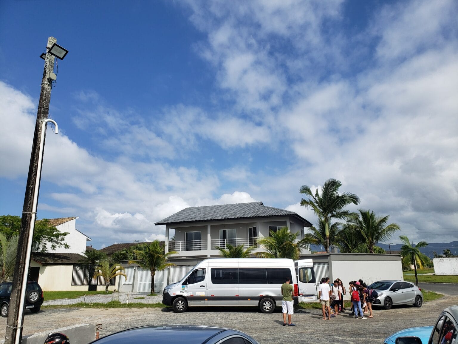 van de viagem parada em frente a casa de praia com pessoas guardando seus pertences