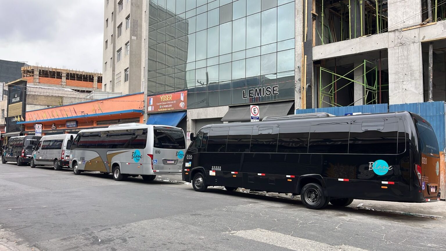 Ônibus e vans parados em frente a prédio