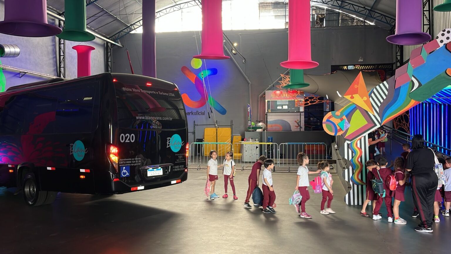Crianças em quadra de escola com micro ônibus estacionado