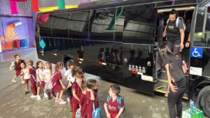 Professora de escola infantil descendo de ônibus com fila de crianças do lado de fora